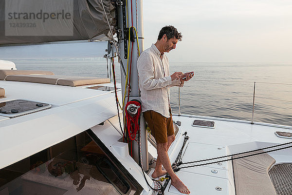 Marure man on catamaran  using smartphone