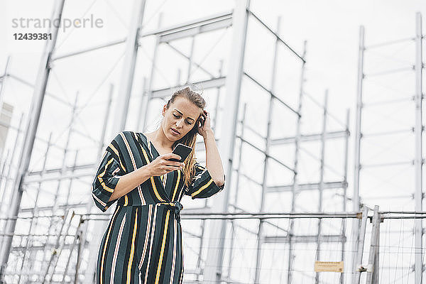 Young woman using cell phone at scaffolding
