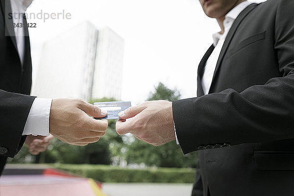 Two businessmen handing over credit card