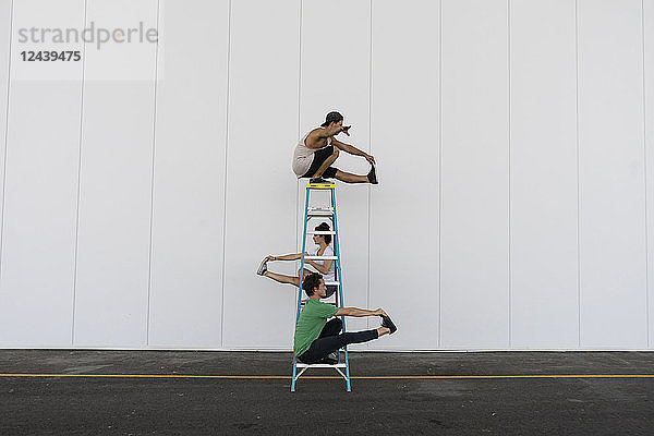 Three acrobats doing tricks on a ladder