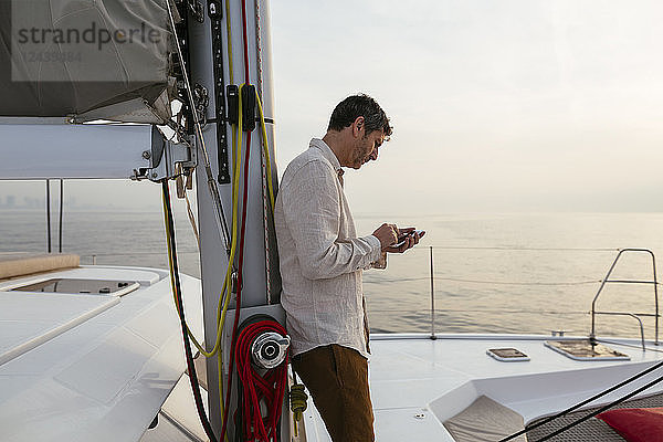 Marure man on catamaran  using smartphone