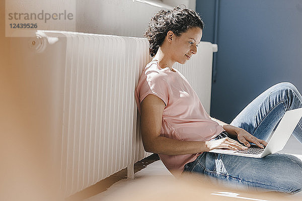 Woman sitting on ground  using laptop