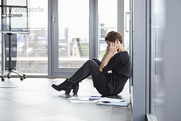 Overstressed businesswoman sitting on the floor in office