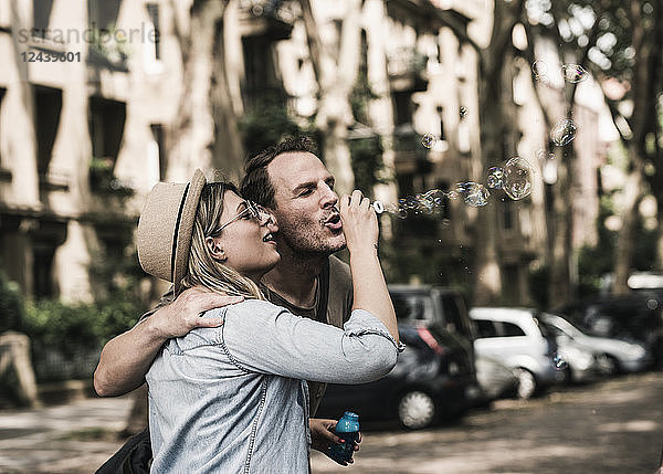 Couple blowing soap bubbles in the city together