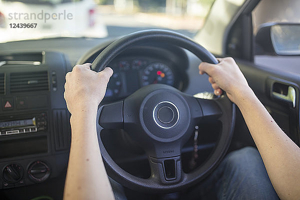 Male hands in car holding steering wheel