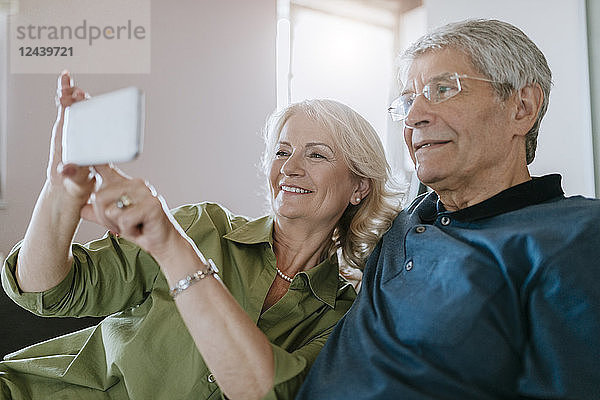 Senior couple at home sitting on couch taking a selfie