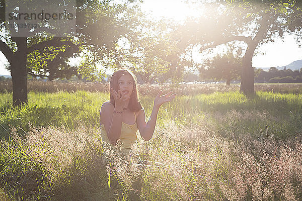 Young girl sitting on meadow at summer evening