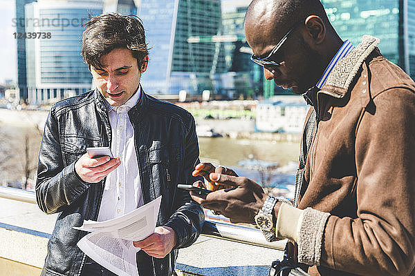 Russia  Moscow  two businessmen using smartphones in the city