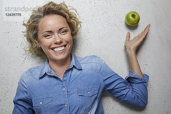 Portrait of happy blond woman with green apple