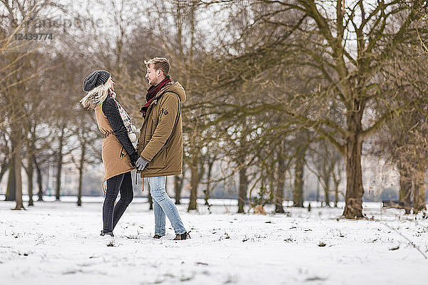 Young couple in love standing hand in hand in a park in winter