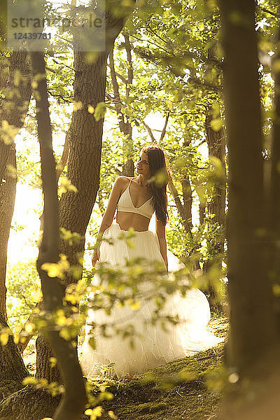 Young woman in forest wearing tulle skirt and bra