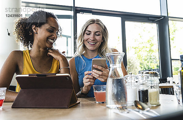 Best friends meeting in cafe  talking and sharing news  using digital tablet