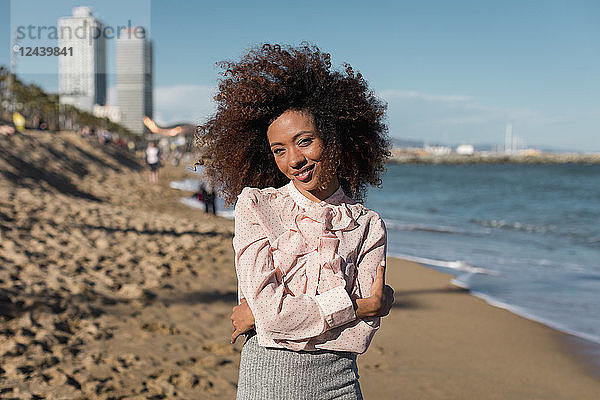 Portrait of smiling beautiful young woman with afro hairdo standing on the beach