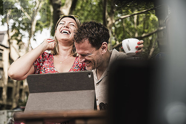 Happy couple with tablet at an outdoor cafe