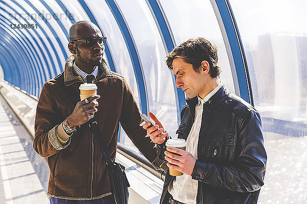 Two businessmen with coffee to go and smartphone