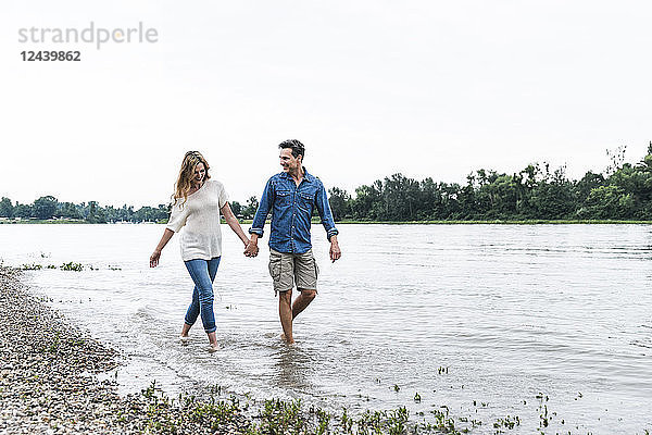 Happy couple wading in river