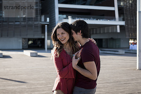 Happy affectionate young couple standing on city square