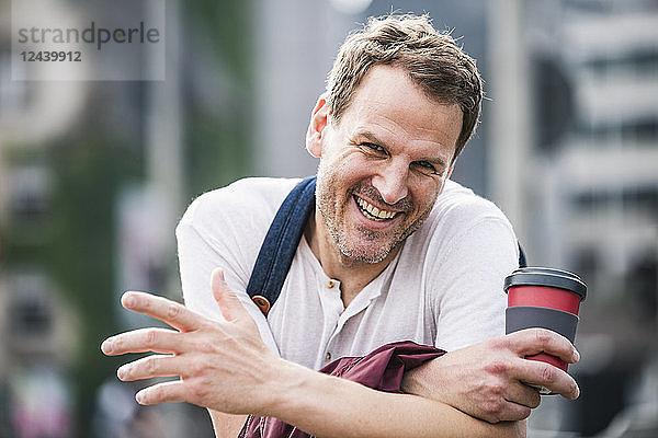 Portrait of happy man with takeaway coffee in the city