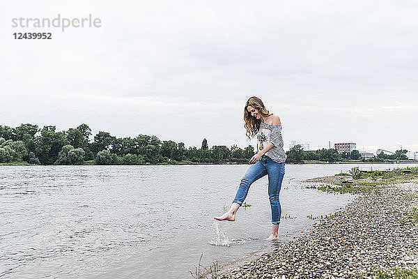 Smiling woman splashing water in a river