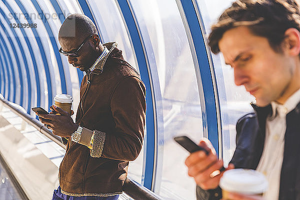 Businessmen with coffee to go using smartphone