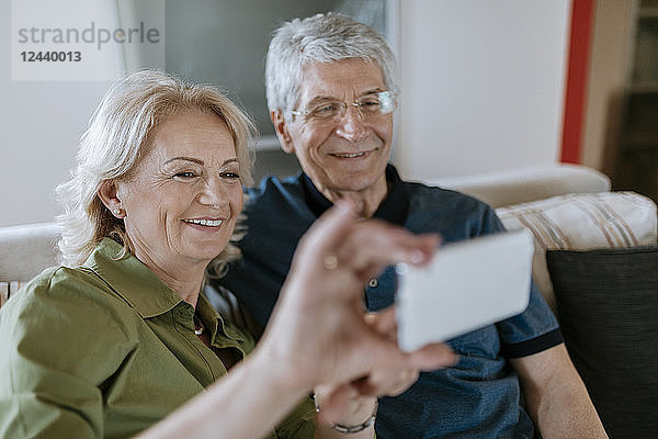 Senior couple at home sitting on couch taking a selfie