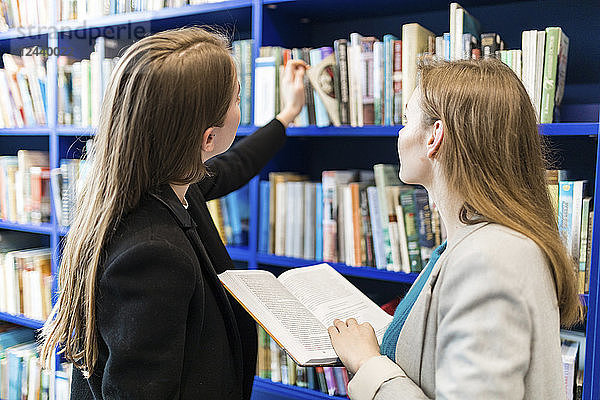 Two teenage girl in a public library choosing books