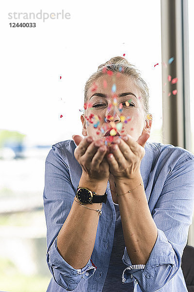 Happy businesswoman blowing confetti  celebrating success