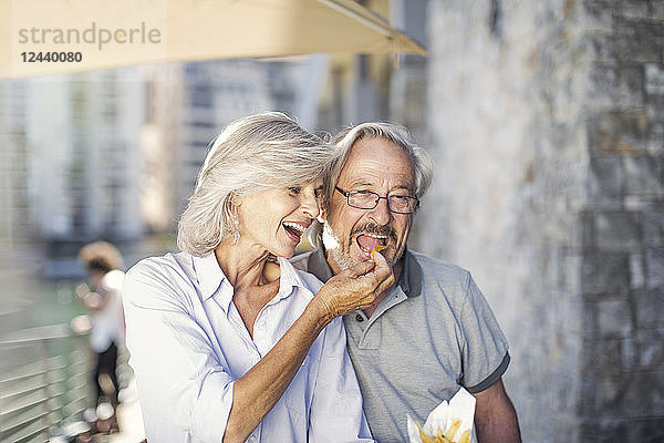 Senior couple taking a city break  eating French fries