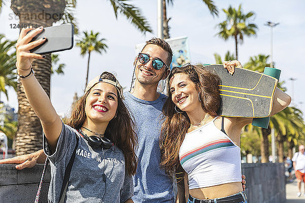 Three happy friends with skateboard taking a selfie