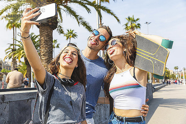 Three playful friends with skateboard taking a selfie