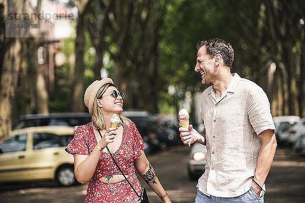 Happy couple with ice cream cones walking in the city