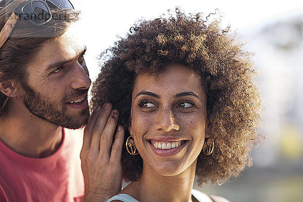 Happy young couple  man whispering into woman's ear