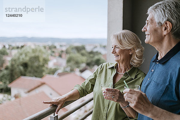 Smiling senior couple on balcony looking at view