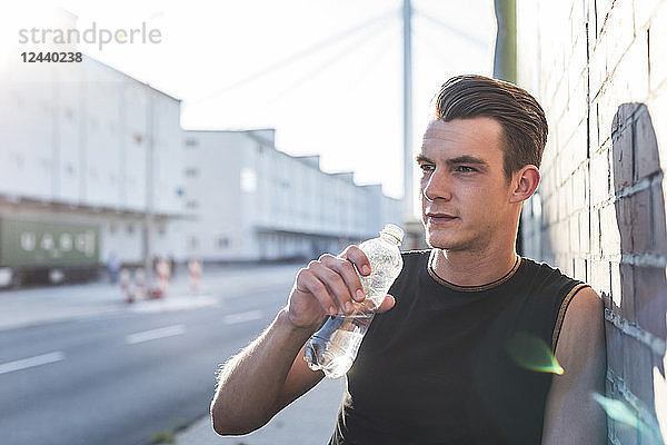 Germany  Mannheim  Young athlete in the city with bottle of water  portrait
