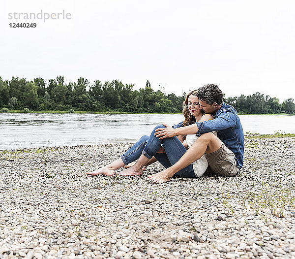 Affectionate couple sitting at the riverside