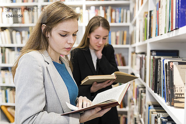 Portrait of teenage girl reading book in a public library