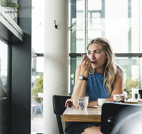 Young woman in cafe  drinking coffee and eating sweets