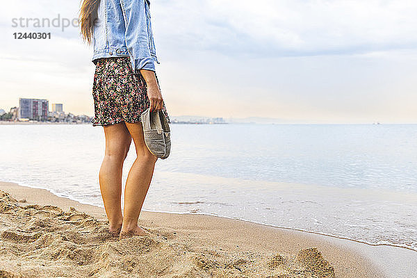 Spain  Barcelona  woman standing barefoot on the beach