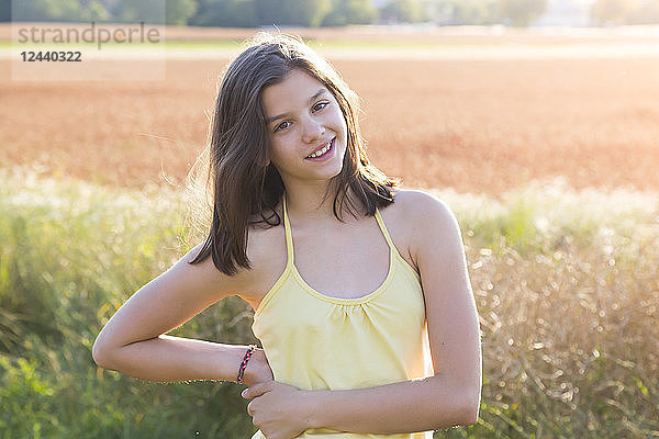 Smiling young girl on meadow at summer evening