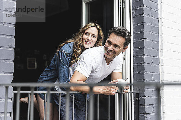 Happy couple in nightwear at home at balcony door