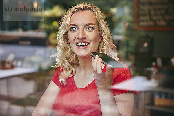 Portrait of happy blond woman using smartphone in a cafe