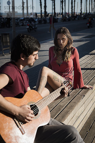 Spain  Barcelona  couple with a guitar sitting on a bench at seaside promenade