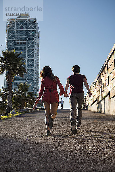 Spain  Barcelona  couple running hand in hand in the city