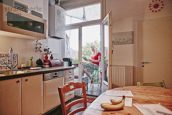 Pregnant woman sitting on balcony looking at photo book