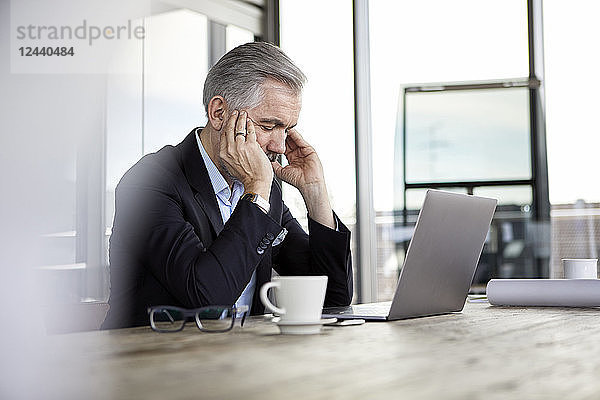 Businessman with headaches sitting at desk in office