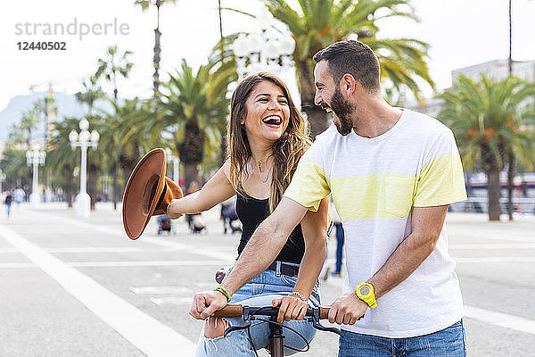 Spain  Barcelona  couple having fun and sharing a ride on a bike together on seaside promenade