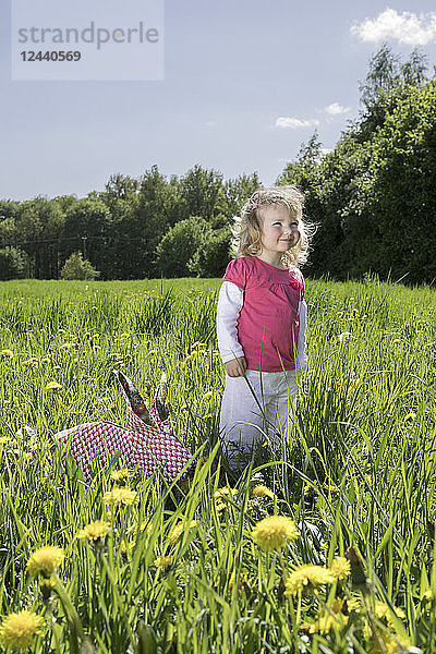 Little girl with origami rabbit on meadow