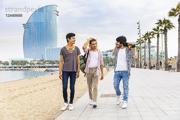 Spain  Barcelona  three friends walking on beach promenade