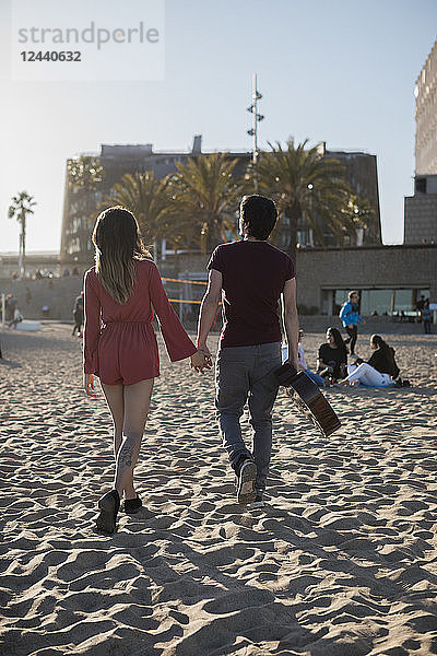 Spain  Barcelona  couple with a guitar walking on the beach