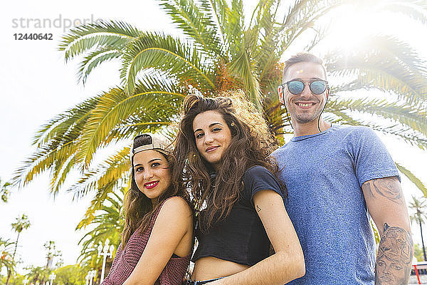 Portrait of smiling friends at a palm tree